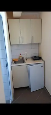 a small kitchen with white cabinets and a sink at MD Apartmani Canj in Čanj