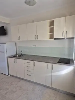 a kitchen with white cabinets and a sink and a refrigerator at Villa Blanca in Petrovac na Moru