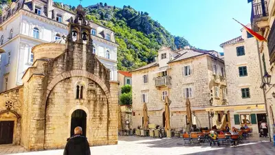 a woman walking in front of an old building at OLD TOWN 303 in Kotor