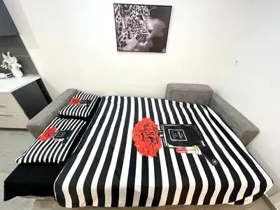 a bed with black and white striped sheets and red roses at Apartment Diamond -modern and lovely seaside studio apartment in Kotor