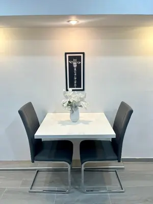a white table with black chairs and a vase with flowers at Apartment Diamond -modern and lovely seaside studio apartment in Kotor