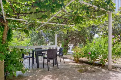 a table and chairs under a pergola in a garden at Pearl of Budva in Budva