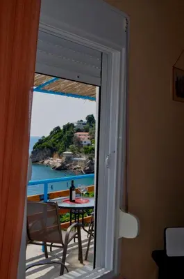 a door open to a balcony with a table and the ocean at Sunset in Ulcinj