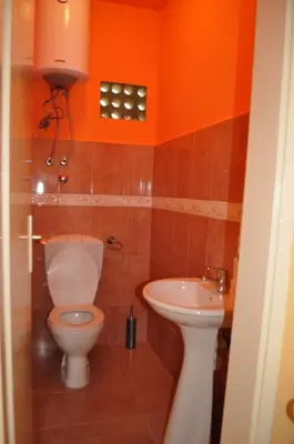 an orange bathroom with a toilet and a sink at Sunset in Ulcinj