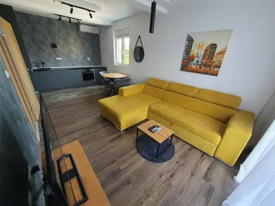 a living room with a yellow couch and a table at JOX Apartment in Podgorica