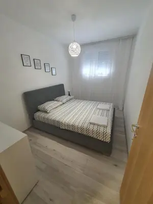 a bedroom with a bed in a white room at JOX Apartment in Podgorica