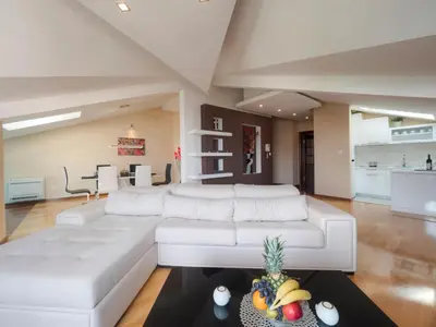 a living room with a large white couch at Skyline Penthouse Budva in Budva