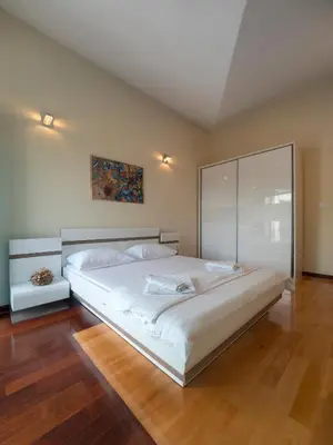 a large white bed in a room with wooden floors at Skyline Penthouse Budva in Budva