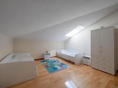 a bedroom with two beds and a cabinet and a rug at Skyline Penthouse Budva in Budva