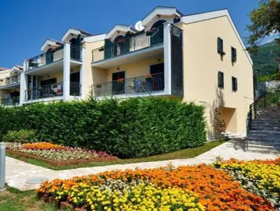 a large white building with flowers in front of it at Villa Deluxe Lastva in Budva