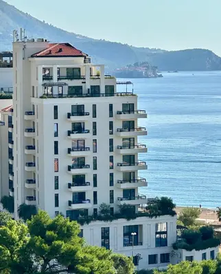 a tall white building next to the water at Casa Al Mare Residence Apartment Lena in Budva