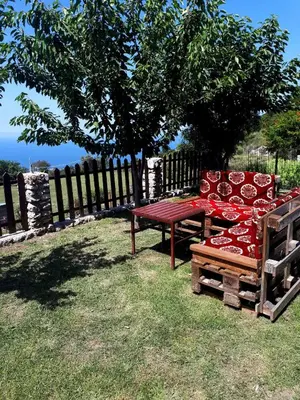 a red bench sitting in the grass under a tree at Etno house Velje Selo in Bar