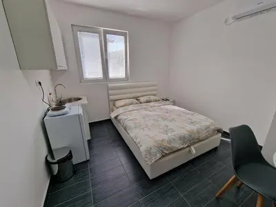 a small bedroom with a bed and a window at Apartman Tolosi in Podgorica