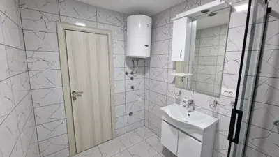 a white bathroom with a sink and a mirror at Apartman Tolosi in Podgorica