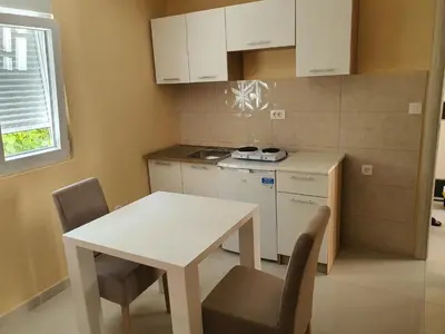 a small kitchen with a white table and chairs at Apartman Tolosi in Podgorica