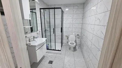 a white bathroom with a toilet and a sink at Apartman Tolosi in Podgorica