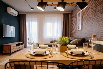 a dining room with a table with plates and wine glasses at Comfortable Apartment at CITY QUART in Podgorica