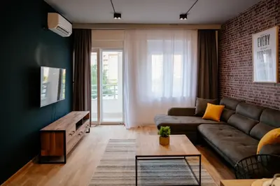 a living room with a couch and a brick wall at Comfortable Apartment at CITY QUART in Podgorica