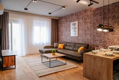 a living room with a couch and a brick wall at Comfortable Apartment at CITY QUART in Podgorica
