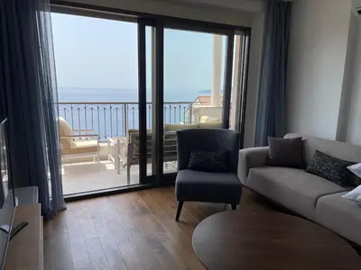 a living room with a couch and chair and a balcony at Lux Apartment Kamenovo in Sveti Stefan