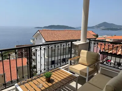 a balcony with a chair and a view of the water at Lux Apartment Kamenovo in Sveti Stefan