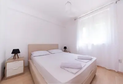 a white bedroom with a bed and a window at Sunshine in Kotor