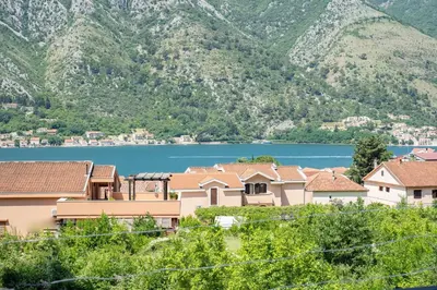 a village with a lake and mountains in the background at Sunshine in Kotor
