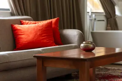 a living room with a couch and a table with a red pillow at MASHTRA - The Olive House in Ulcinj