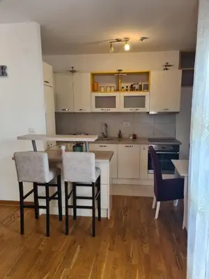 a kitchen with white cabinets and a table and chairs at Apartman Natalia in Podgorica