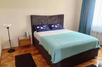 a bedroom with a bed with blue sheets and a lamp at Cute, spacious apt in the heart of the old town in Podgorica