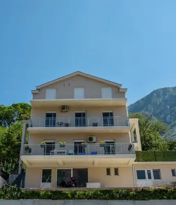 a yellow building with balconies and a mountain in the background at Java apartments - S & J in Dobrota