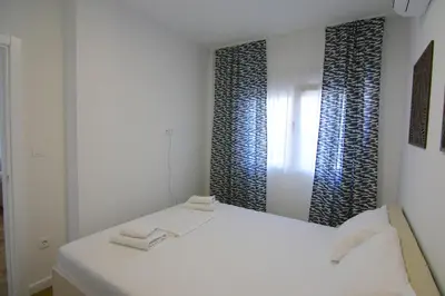 a white room with a bed and a mirror at Apartments LORA Zmajeva, 7 in Budva