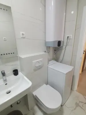 a white bathroom with a toilet and a sink at Apartments LORA Zmajeva, 7 in Budva