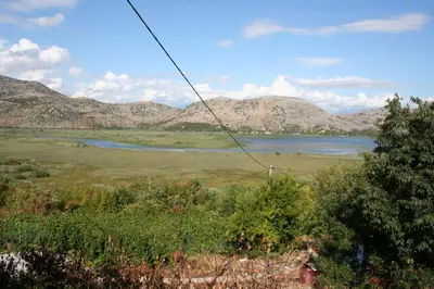 a view of a field with a lake and mountains at SKADAr LAKE SARA 3 DM in Cetinje
