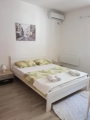 a white bedroom with a bed and a painting on the wall at Apartments Peđa in Sveti Stefan