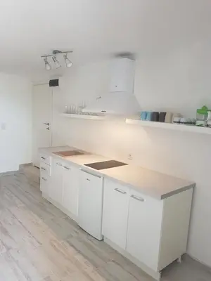 a kitchen with white cabinets and a wooden counter top at Apartments Peđa in Sveti Stefan