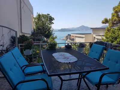 a table and chairs on a balcony with a view of the water at Apartments Peđa in Sveti Stefan