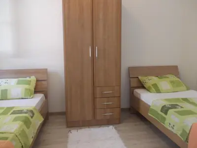 a bedroom with two beds and a wooden cabinet at Apartments Peđa in Sveti Stefan