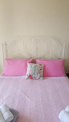 a pink bed with pink pillows and a white headboard at Lighthouse Apartments in Budva