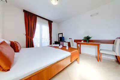 a bedroom with a bed and a desk and a chair at Petrovac Holiday Apartments in Petrovac na Moru