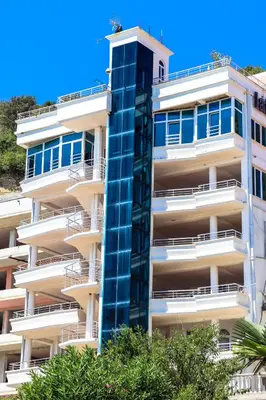 a tall white building with blue windows at Rosa Negra in Ulcinj