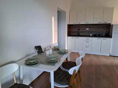 a kitchen with a white table and chairs and a kitchen with white cabinets at Apartmani EMMA in Kotor