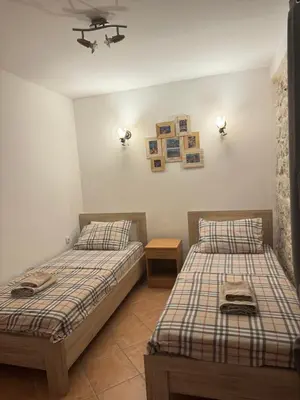 two beds in a room with two tables and pictures on the wall at Cozy Little House Kotor in Kotor