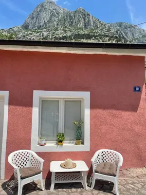 a red building with two chairs and a table at Cozy Little House Kotor in Kotor