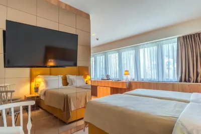 a hotel room with two beds and a flat screen tv at HOTEL AGAPE in Bar