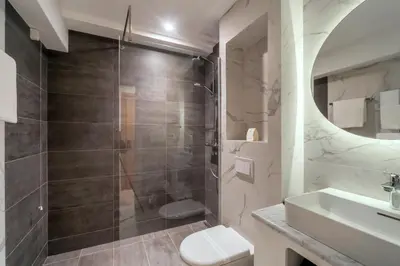 a bathroom with a shower and a toilet and a sink at HOTEL AGAPE in Bar