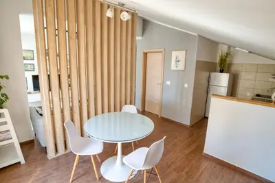 a dining room with a table and white chairs at Cozy rooftop apartment with the city view in Budva