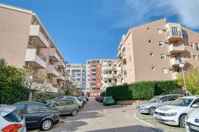 a parking lot with cars parked in front of buildings at Cozy rooftop apartment with the city view in Budva
