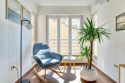 a living room with a blue chair and potted plants at Cozy rooftop apartment with the city view in Budva