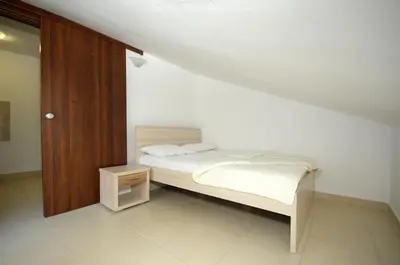 a bedroom with a white bed and a wooden cabinet at Apartments Anita in Budva